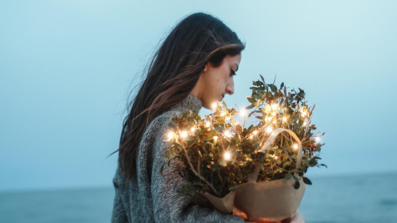 Frau am Strand mit Blumen und Lichterkette